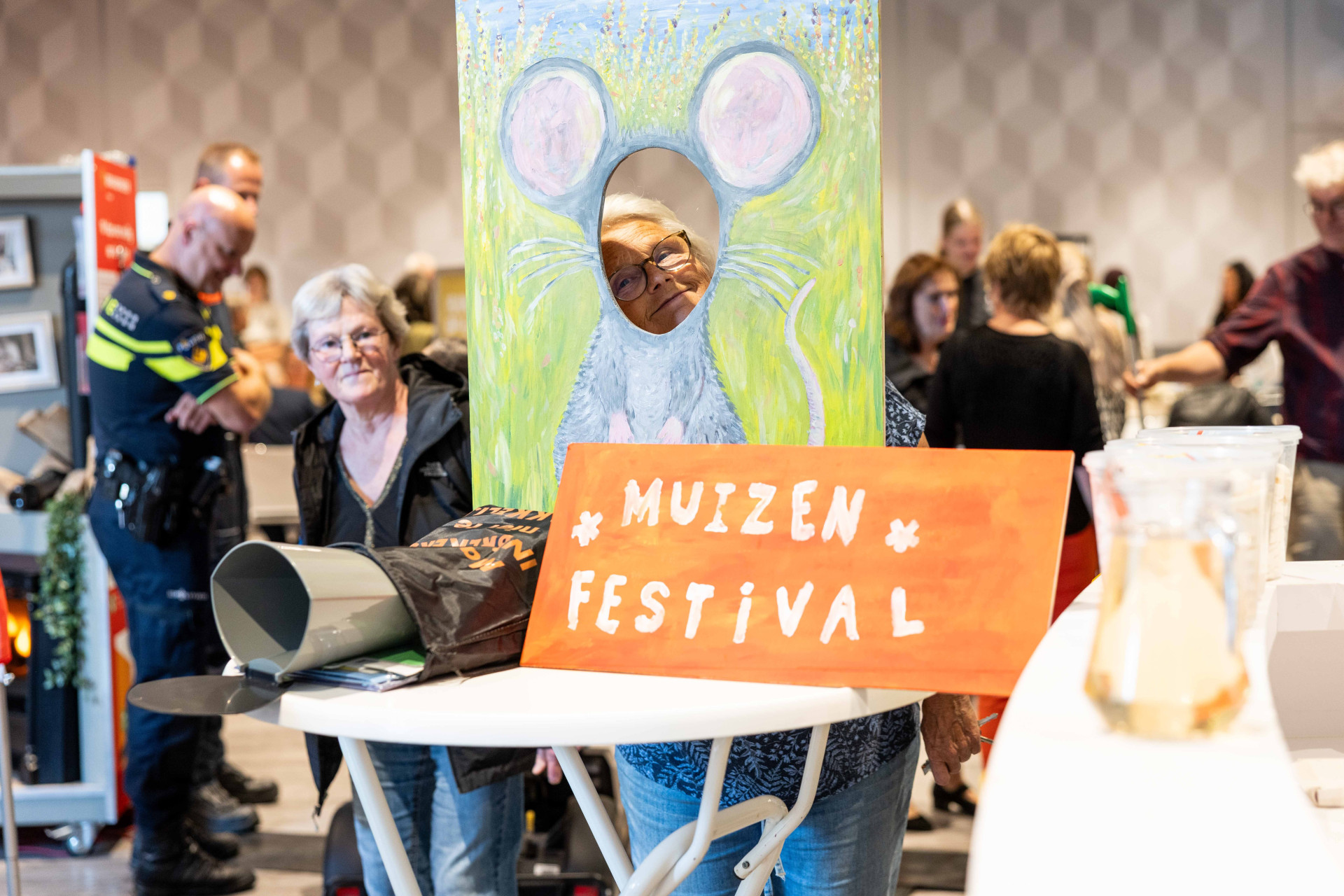Persoon poseert voor kartonnen muis met bord "Muizen Festival" in de Vrijheidswijk in Leeuwarden.