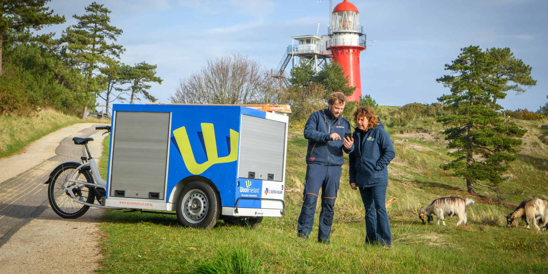 Wijkconsulent en vakman van WoonFriesland staan bij de nieuwe bakfiets op Vlieland.