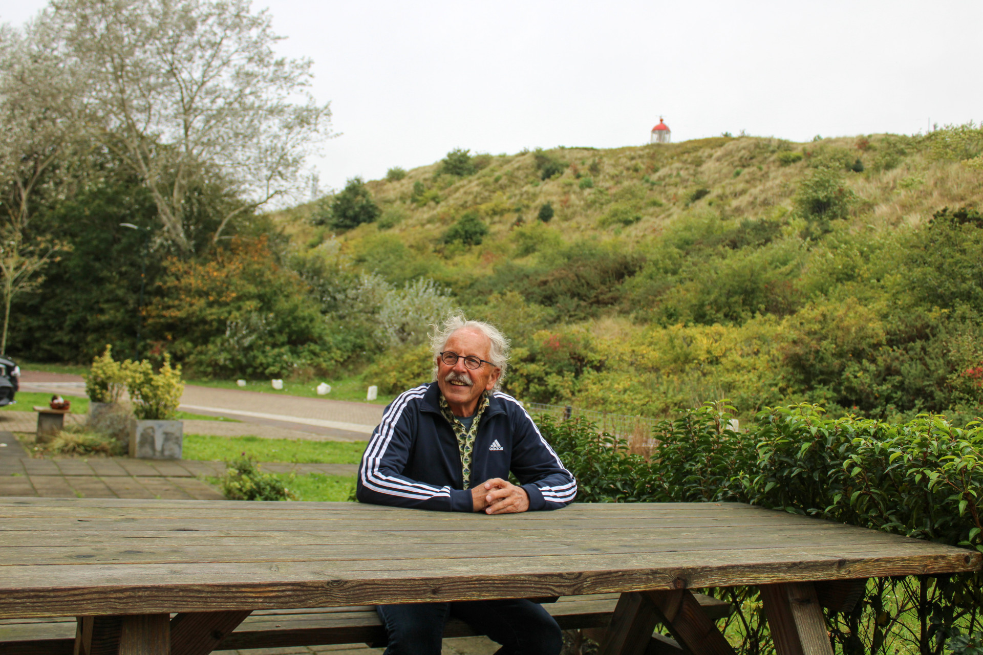 Bewoner poseert voor de duinen, met op de achtergrond de vuurtoren van Vlieland.