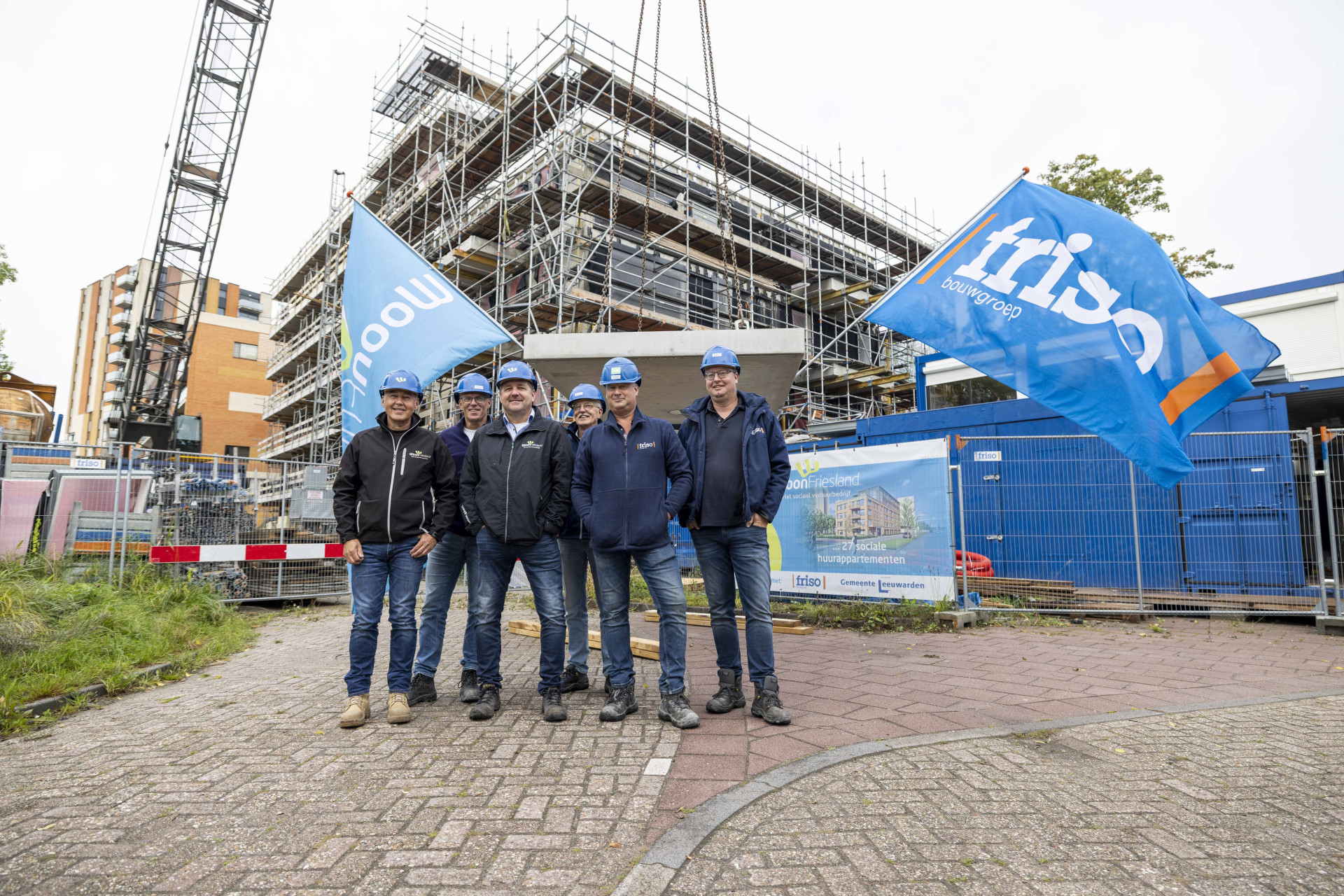 Trotse medewerkers van WoonFriesland en Friso Bouwgroep poseren bij het hoogstepunt van De Wissesdwinger in Leeuwarden.