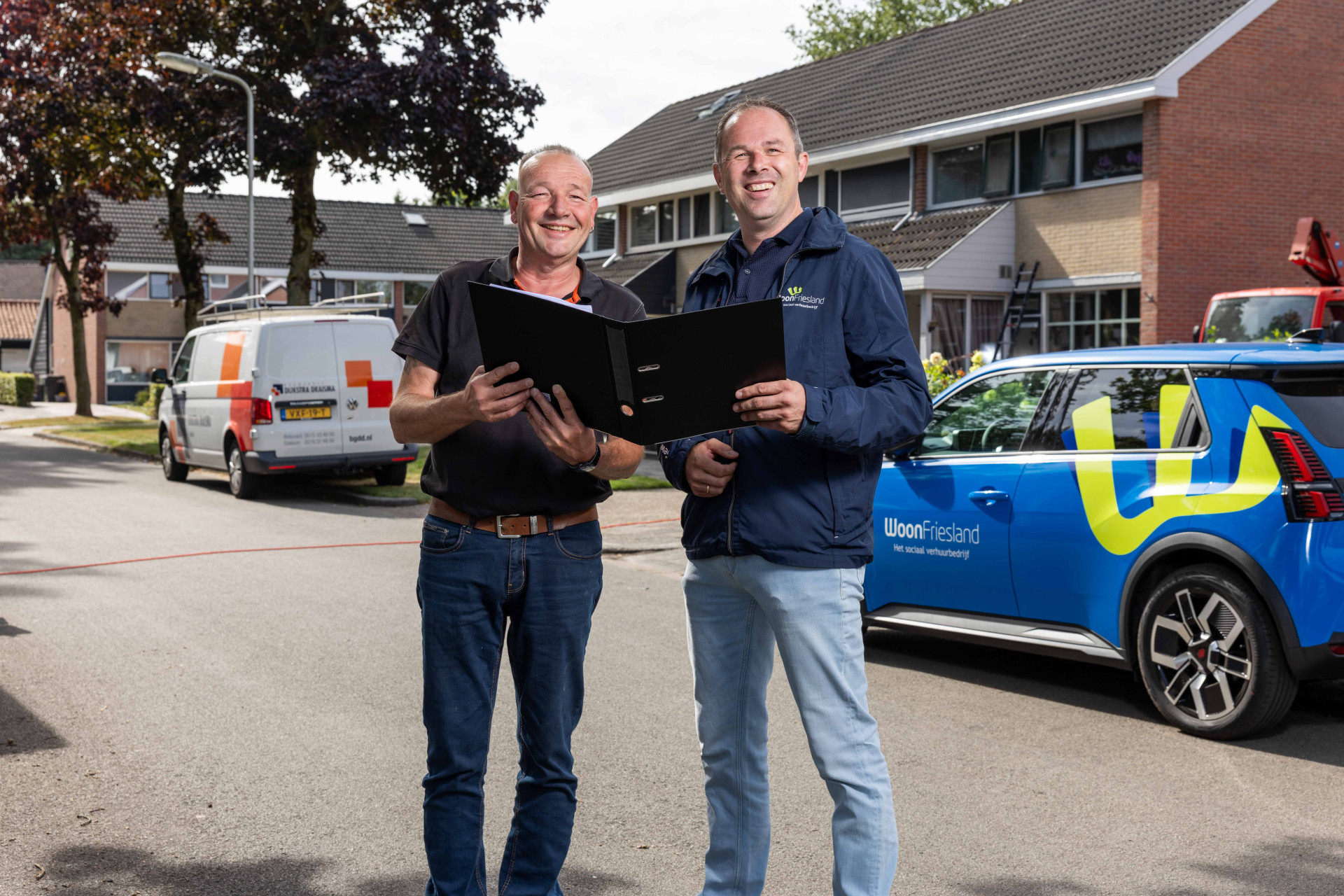 Twee medewerkers van WoonFriesland poseren in de wijk in de gemeente Achtkarspelen.